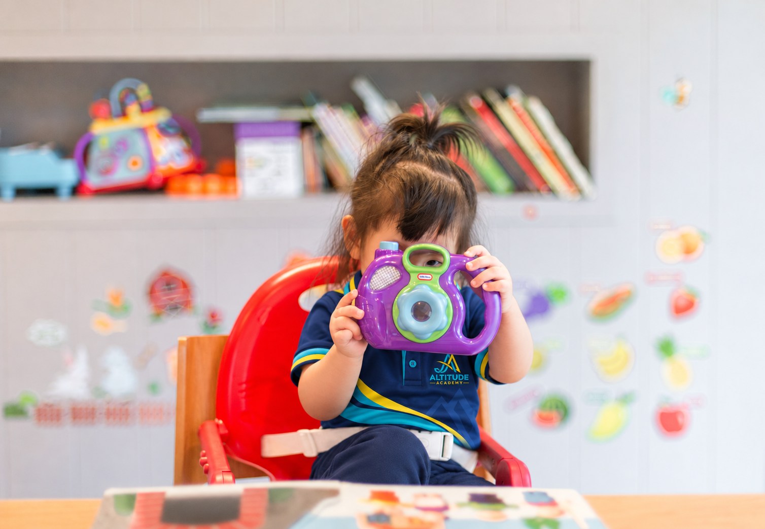 A toddler playing with a toy camera